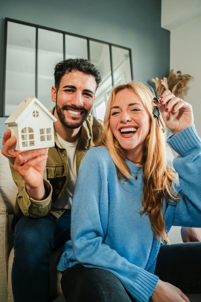 Vertical. couple celebrating a beginning at their new home holding the key of the house. Real estate